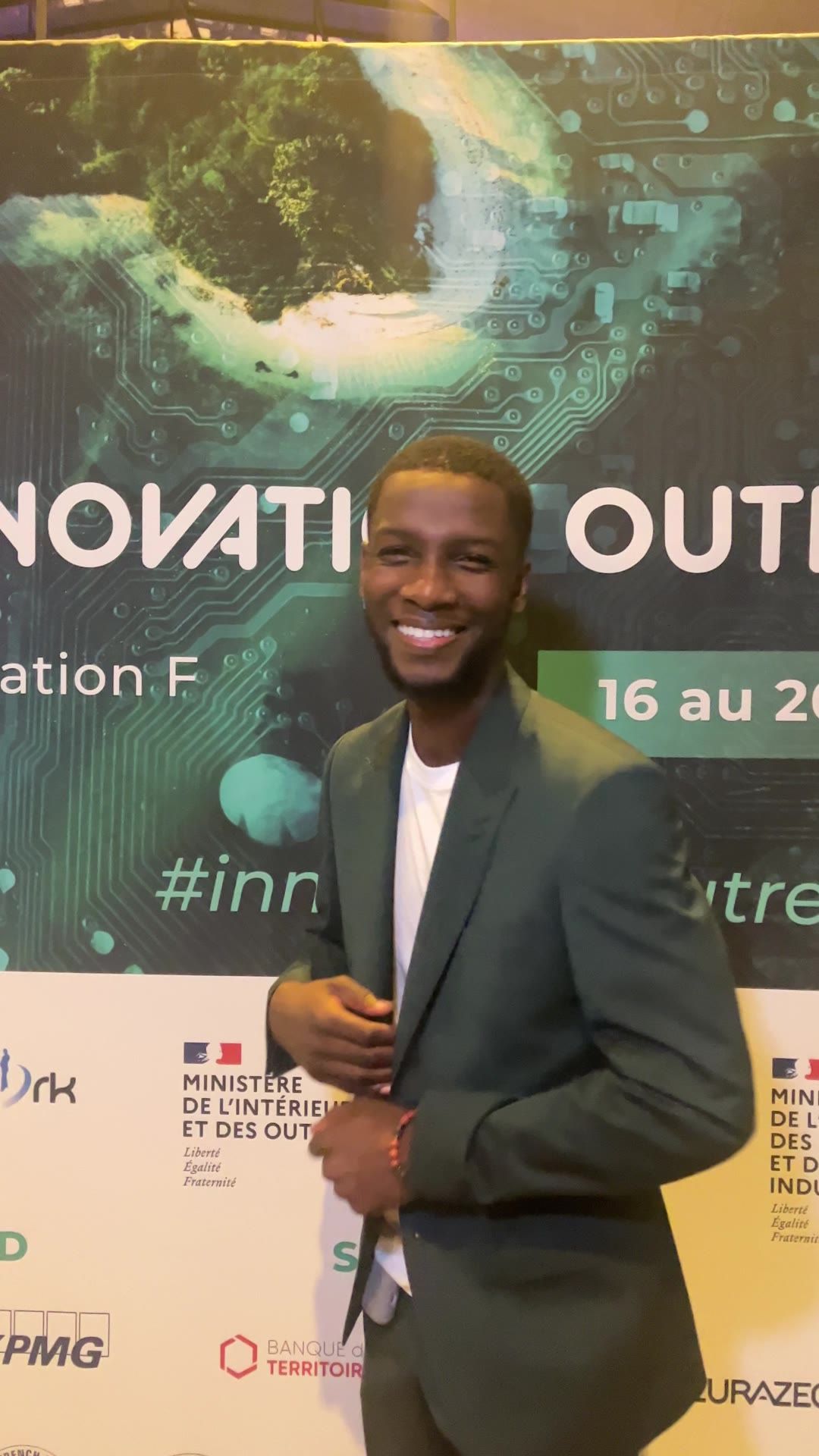 Axel Loupeda souriant, micro en main, devant le panneau Innovation Outre-mer