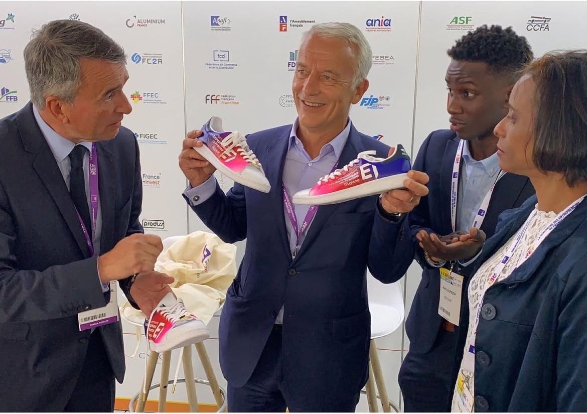 Axel Loupeda présente des baskets Belpair aux couleurs du MEDEF à trois dirigeants, sur un stand de la REF 2021